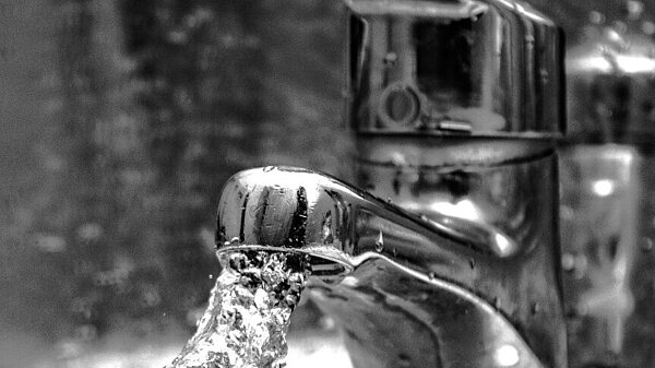 A black and white image of a flowing tap, text says "Tell Thames Water: Scrap the Price Hike!"