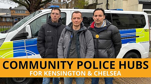 Lib dem activists standing in front of a police van, text on the bottom says "community police hubs for Kensington & Chelsea"